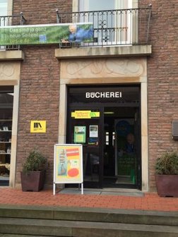 Eingangstür der Bücherei. An der Tür steht Bücherei. Darüber hängt ein Banner mit der Aufschrift "Das sind ganz neue Seiten". 